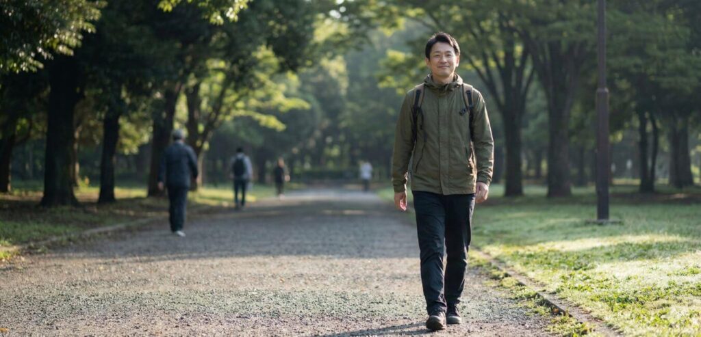 朝の公園を歩く男性